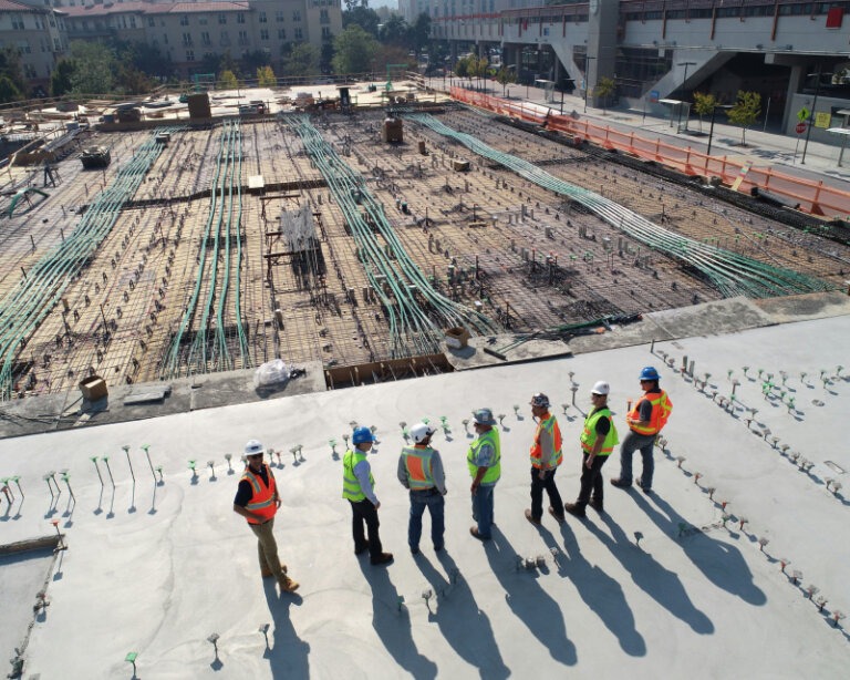 Reihe von Bauarbeitern schreitet über eine großflächige Baustelle