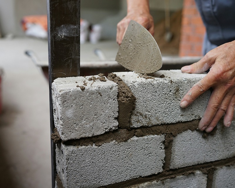 Maurer setzt einen Ziegelstein in eine Mauer