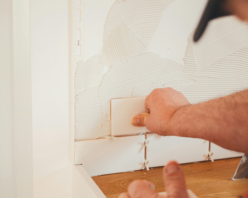 Handwerker verfugt Mosaikfliesen an einer Wand