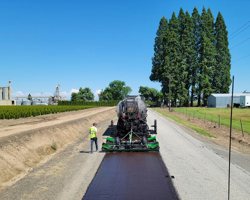 Straßenfertiger verlegt frischen Asphalt auf Landstraße