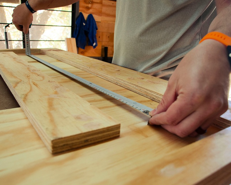 Zimmerer misst ein Holzbrett mit dem Zollstock aus